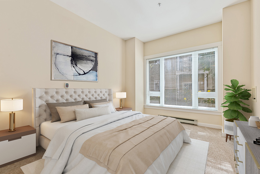 A modern bedroom in the 143 Apartment features beige walls and a tufted white bed with matching beige bedding. Two bedside tables with lamps flank the bed. There's a large window with blinds, a potted plant, and abstract art above the headboard. The room is well-lit and inviting.